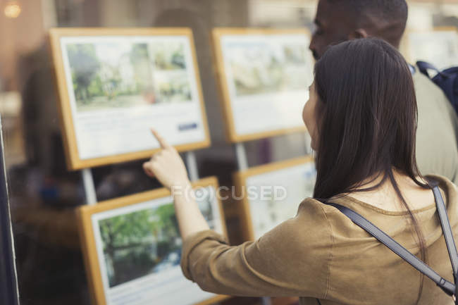 Giovane coppia in cerca di annunci immobiliari a storefront — Foto stock