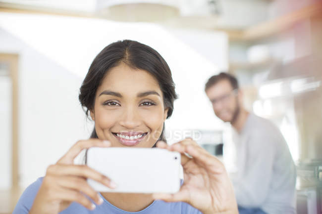 Portrait femme souriante à l'aide d'un téléphone caméra — Photo de stock