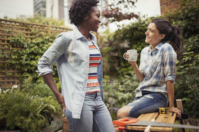 Жінки п'ють каву і розмовляють, роблять проект на патіо — стокове фото