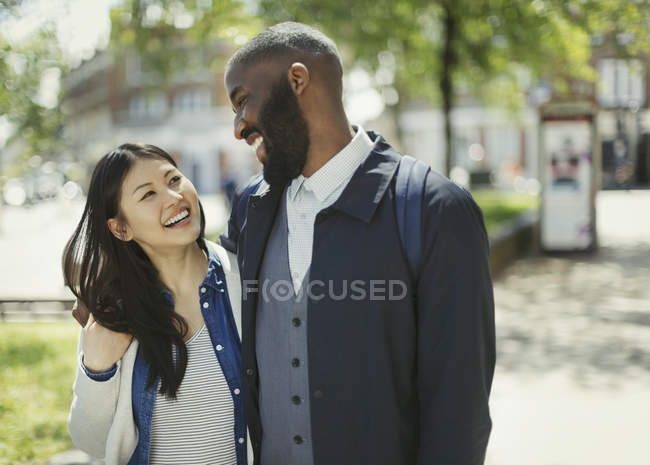 Couple affectueux riant dans un parc urbain ensoleillé — Photo de stock