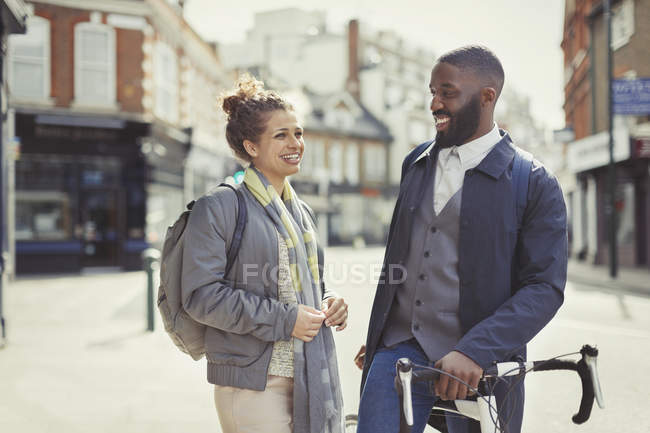 Pareja sonriente viajando con bicicleta en la soleada calle urbana - foto de stock
