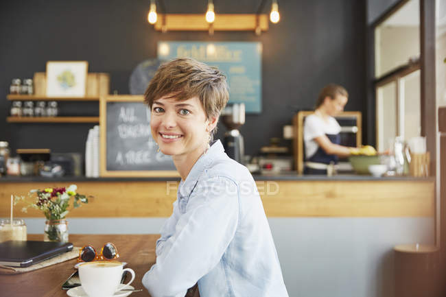 Ritratto donna sorridente bere caffè al tavolo del caffè — Foto stock