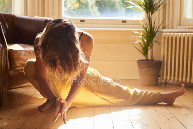 Mujer elegante practicando yoga lado embestida en ventana soleada - foto de stock