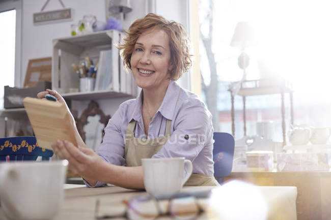Portrait smiling mature female artist painting wood in art class workshop — Stock Photo