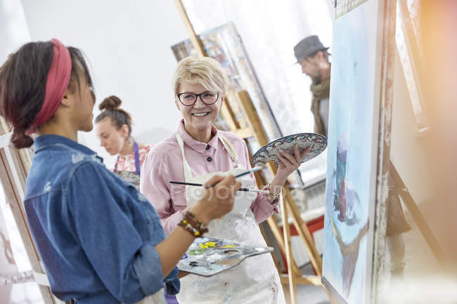 Усміхнені художниці з пензлями та палітрою живопису в студії арт-класу — стокове фото