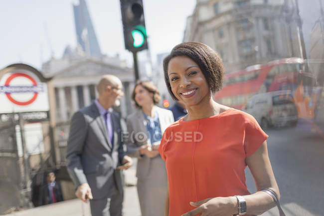Retrato sonriente mujer de negocios en la soleada calle urbana de la ciudad, Londres, Reino Unido - foto de stock