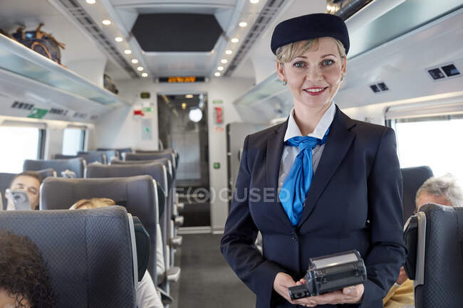 Asistente femenina confiada en retratos en el tren de pasajeros - foto de stock