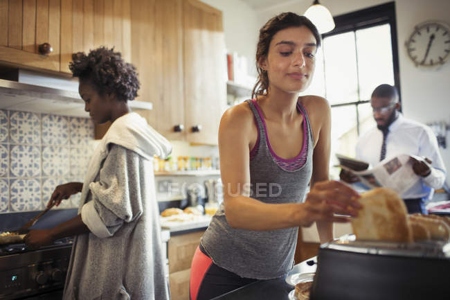 Woman toasting bread in toaster in kitchen — Stock Photo