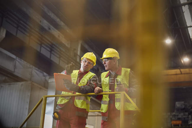 Stahlarbeiter mit Klemmbrett sprechen auf Plattform im Stahlwerk — Stockfoto