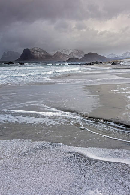 Montanhas acidentadas atrás do frio, maré de praia oceânica, Storsandnes, Lofoten, Noruega — Fotografia de Stock