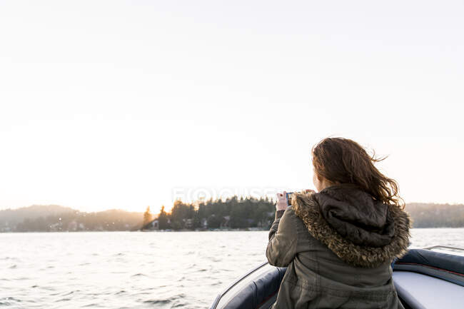 Femme utilisant un téléphone de caméra, photographiant lac tranquille — Photo de stock