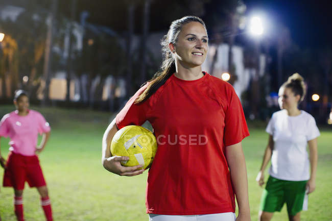 Портрет впевнена, усміхнена молода жінка-футболістка на полі вночі — стокове фото