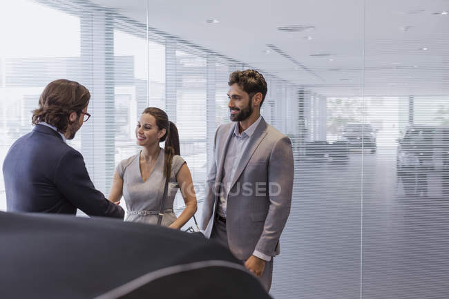 Autoverkäufer begrüßt Paar Kunden im Autohaus — Stockfoto