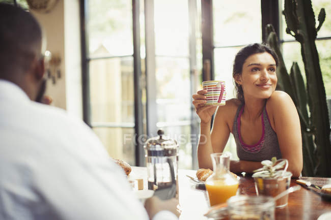 Sorrindo mulher bebendo café na mesa de café da manhã — Fotografia de Stock