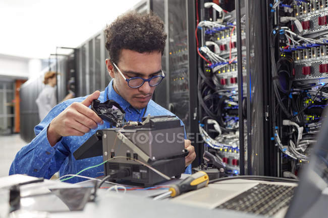 Чоловічий IT технік фіксує обладнання в серверній кімнаті — стокове фото