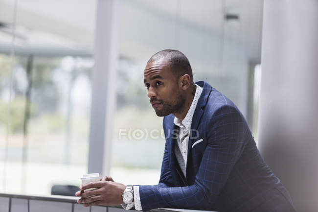 Серьезный бизнесмен пьет кофе в офисе — стоковое фото
