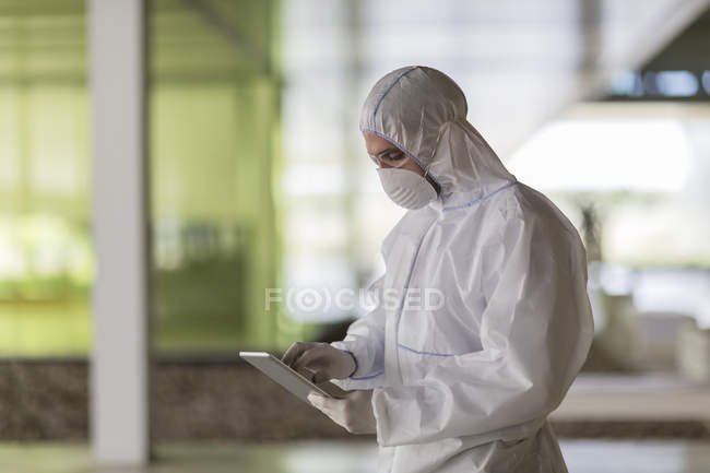 Científico en traje limpio usando tableta digital - foto de stock