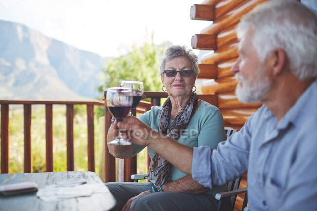 Активная пожилая пара пьет бокалы с красным вином на балконе — стоковое фото