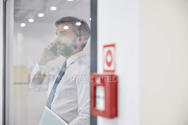 Hombre supervisor hablando en el teléfono celular en la ventana en la fábrica - foto de stock