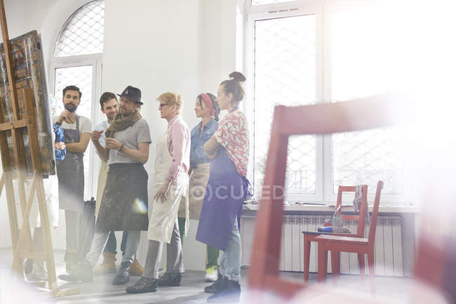 Art students and instructor discussing painting in art class studio — Stock Photo