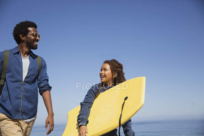 Pai e filha carregando prancha de boogie na praia ensolarada verão — Fotografia de Stock