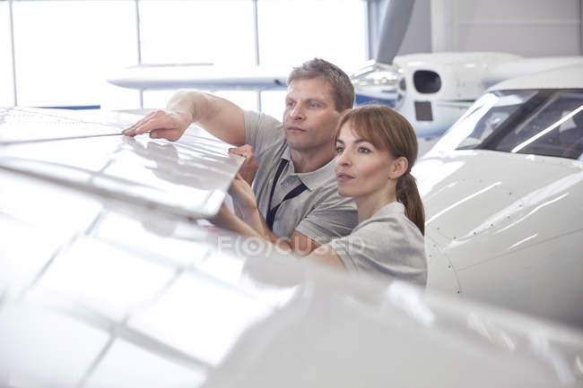 Ingénieurs mécaniciens examinant aile d'avion dans le hangar — Photo de stock