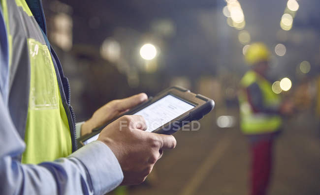 Close up steelworker supervisor using digital tablet in steel mill — Stock Photo