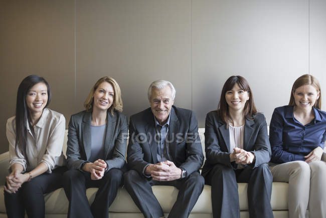 Portrait smiling business people in a row on sofa — Stock Photo