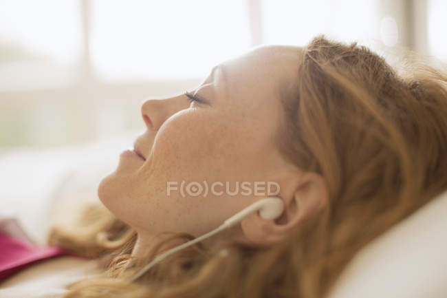 Крупним планом спокійна жінка з навушниками, що слухають музику — стокове фото