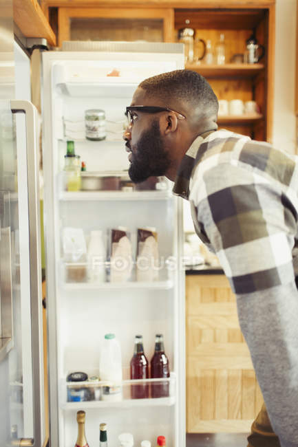 Jovem olhando para a geladeira — Fotografia de Stock