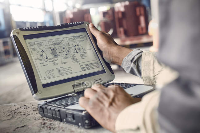 Ingenieur mit Laptop, überprüft Baupläne in Stahlwerk — Stockfoto