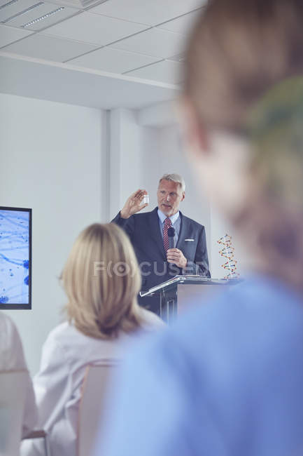 Pharmaceutical businessman explaining medication at podium at conference — Stock Photo