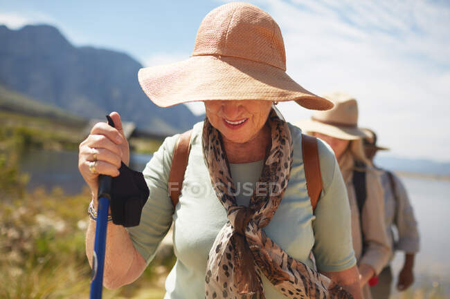 Active senior woman in sun hat hiking — Stock Photo