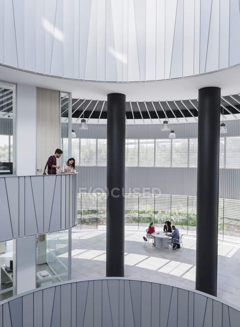 Ділові люди зустрічаються на архітектурному, сучасному офісному балконі атріуму — стокове фото