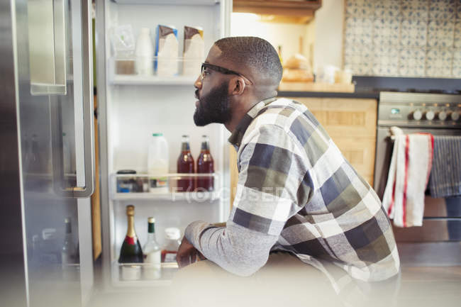 Homem faminto olhando para a geladeira na cozinha — Fotografia de Stock