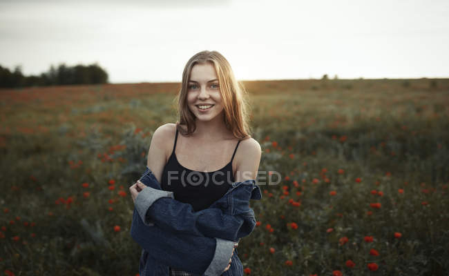 Retrato sonriente joven en el campo rural con flores silvestres - foto de stock