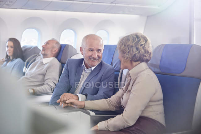 Affectionate mature couple holding hands on airplane — Stock Photo