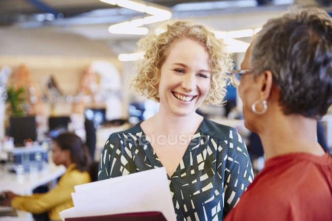 Усміхнені бізнес-леді говорять в сучасному офісі — стокове фото