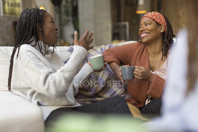Donne che parlano e bevono caffè sul divano — Foto stock