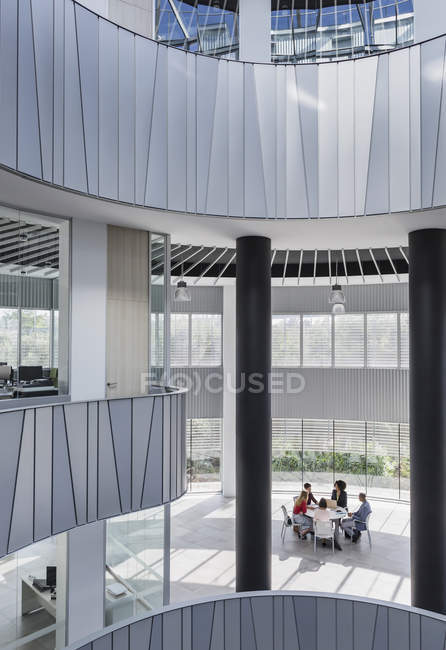 Des gens d'affaires se réunissent à table dans un atrium architectural et moderne — Photo de stock
