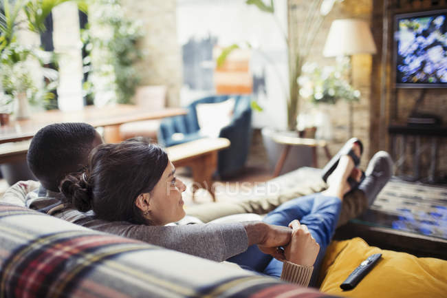 Прихильна молода пара дивиться телевізор на диван у вітальні — стокове фото
