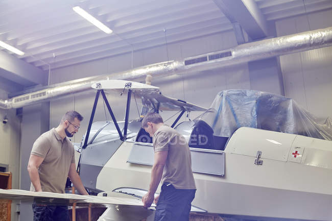 Інженери-чоловіки складають літак в ангарі — стокове фото