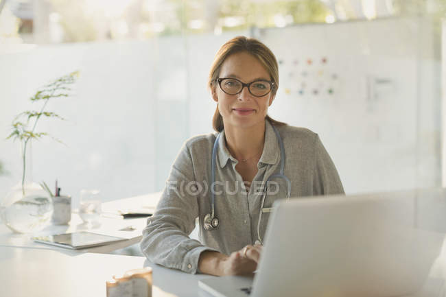 Retrato médico confiante do sexo feminino trabalhando no laptop no consultório do médico — Fotografia de Stock