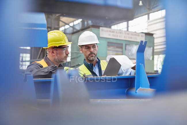 Hombre capataz y trabajador revisando el papeleo en la fábrica - foto de stock