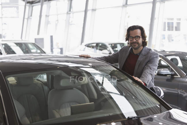 Portrait souriant client masculin faisant des emplettes pour une nouvelle voiture dans la salle d'exposition concessionnaire automobile — Photo de stock