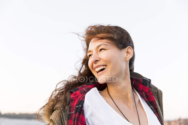 Усміхнена, захоплена жінка дивиться через плече — стокове фото