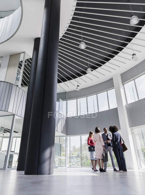 Business people talking in modern office atrium — Stock Photo