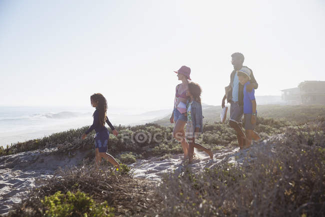 Familia caminando por el soleado sendero de playa de verano - foto de stock