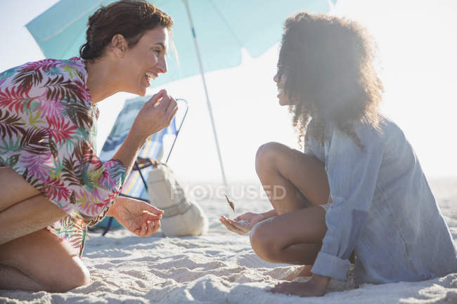 Mãe e filha brincando na areia na ensolarada praia de verão — Fotografia de Stock