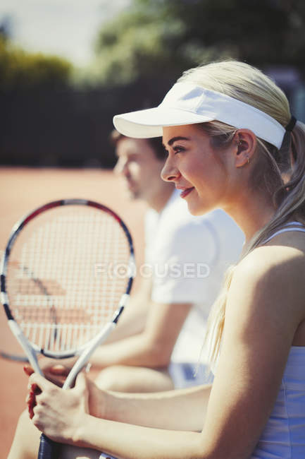 Smiling, confident female tennis player holding racket on sunny tennis court — Stock Photo
